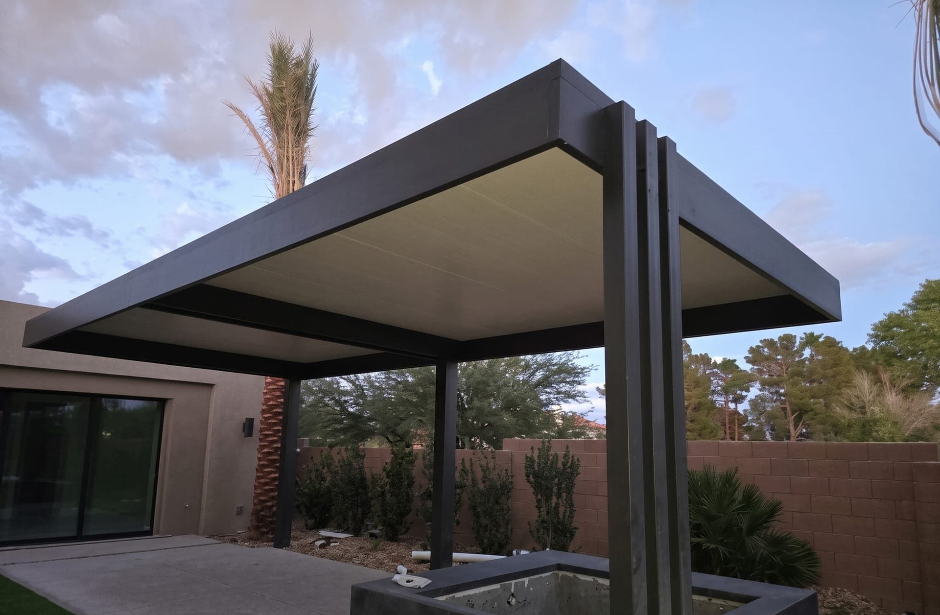 Freestanding 4K Aluminum patio cover with an insulated roof and stacked corner posts over a backyard spa at dusk